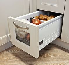 an open drawer in the middle of a kitchen with some food inside and on it's side