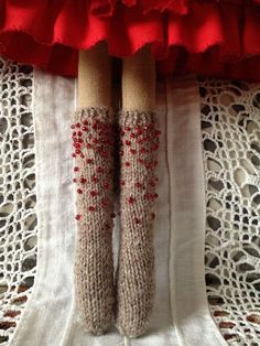 the legs of a doll wearing knitted socks with red beads on them are shown from above