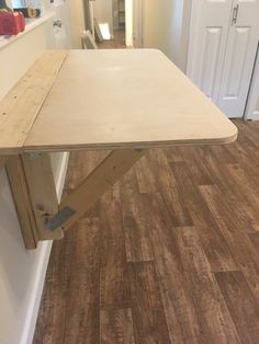 a wooden table sitting on top of a hard wood floor next to a white door