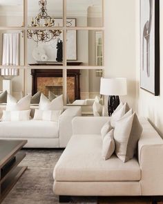 a living room filled with white furniture and a chandelier hanging from the ceiling