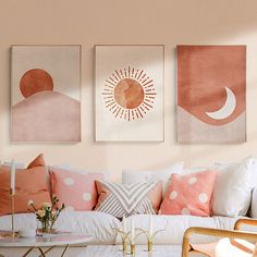 three paintings hang on the wall above a couch with pillows and coffee table in front of it