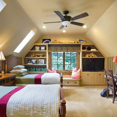 a bedroom with two beds and a desk in the corner under a slanted ceiling