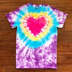 a tie - dyed t - shirt with a heart in the center on a wooden floor