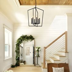 a living room filled with furniture and a chandelier hanging over the top of a wooden floor