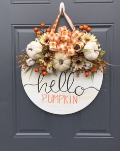 a door hanger with pumpkins and flowers hanging from it's front door