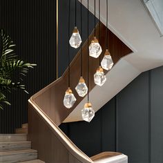 a bunch of lights that are hanging from a stair case next to a potted plant