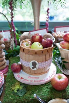 there is a basket full of apples on top of a table with other items around it