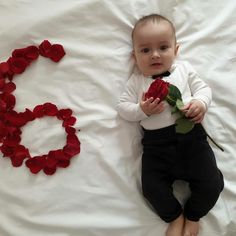 a baby is laying on a bed with roses in the shape of a o sign