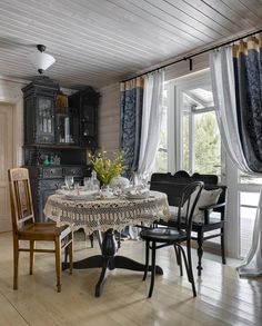 the dining room table is set with four chairs, and there are curtains hanging from the windows