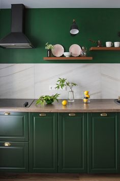 a kitchen with green cabinets and marble counter tops