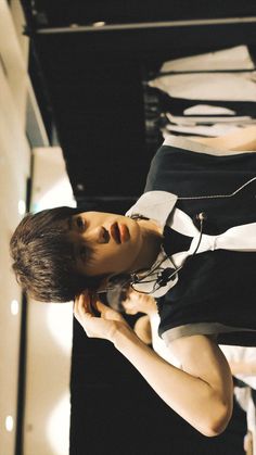 a young man standing in front of a display case holding a cell phone to his ear