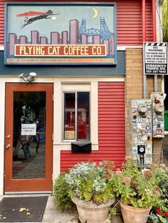 the entrance to flying cat coffee co with potted plants and signs on the building