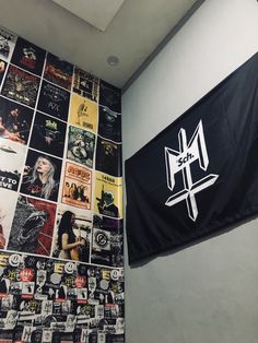 a black and white wall covered in posters next to a flag with the word metal on it