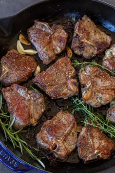 some steaks are cooking in a skillet on the stove top, with rosemary sprigs