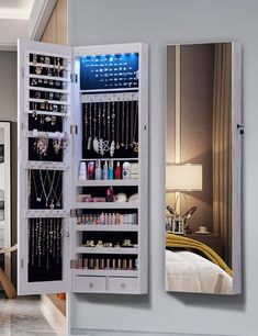 a mirrored wall mounted jewelry cabinet in a bedroom next to a mirror on the wall