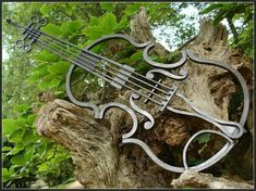 a metal violin sculpture sitting on top of a tree