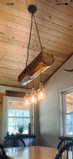 a light fixture hanging from the ceiling in a dining room with wood beams and glass jars