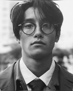 a young man wearing glasses and a suit