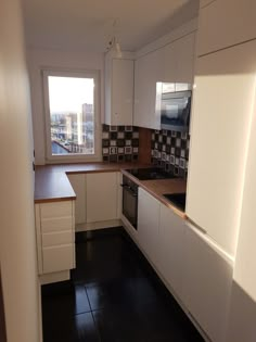 an empty kitchen with white cabinets and black flooring