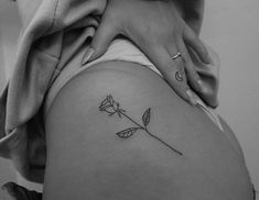 a black and white photo of a woman's thigh with a rose tattoo on it