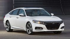 a white honda accord is parked in front of a garage door with its lights on