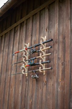 there are many fishing rods attached to the side of a wooden building that is covered in wood planks