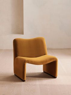 a yellow chair sitting on top of a hard wood floor next to a white wall