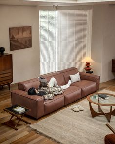 a person laying on a couch in a living room next to a coffee table and lamp