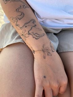 a person with a tattoo on their arm sitting down and holding something in her hand