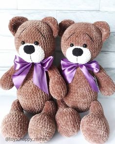 two brown teddy bears sitting next to each other with purple ribbons on their ears and feet