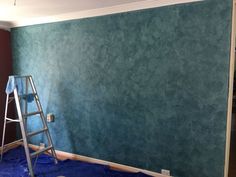 a ladder is standing in front of a wall with blue paint on it and the walls are being painted