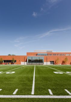 an empty football field in front of a brick building with white lines painted on it