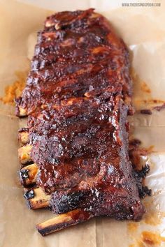 a piece of barbecue ribs sitting on top of wax paper covered in sauce and seasoning