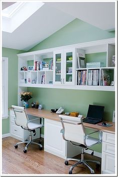 a home office with green walls and white cabinets