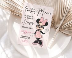 a minnie mouse birthday party card on a plate with palm fronds in the background