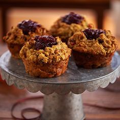 three muffins sitting on top of a cake plate with cranberry topping