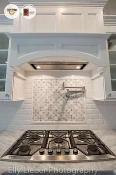 a stove top oven sitting inside of a kitchen next to white cabinets and counter tops