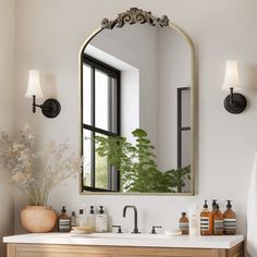 a bathroom with a mirror, sink and plants on the counter top in front of it