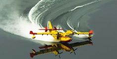 two yellow and red planes flying in the air over water with white spray behind them