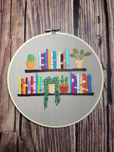 a cross stitch pattern with bookshelves and succulents