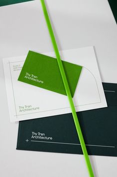 two green and white business cards on top of each other with a pencil in the middle