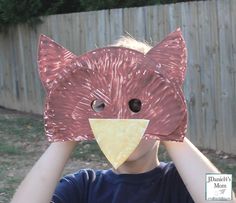 a young boy holding up a piece of paper to his face with an animal mask on it