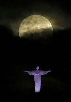 the statue of christ in front of a full moon