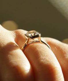 a close up of a person's hand holding a ring with a diamond on it