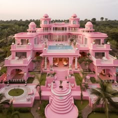 an aerial view of a pink mansion with a pool in the middle and palm trees surrounding it