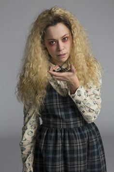 a woman with long blonde hair is holding something in her hand and looking at the camera