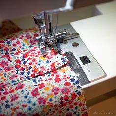 the sewing machine is working on the flowered material that's being sewn