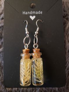 Real dried plants preserved in resin in a glass bottle!  Slimmer bottle is 1cm wide x 2.6cm tall bottles, while the wider bottle is 1.2cm wide x 2.4 cm tall, both attached to silver colored stainless steel hook earrings.  For nature lovers or a fairy vibe, get these unique, handmade earrings! Bottle Earrings, Dry Plants, Hook Earrings, Handmade Earrings, Glass Bottles, Jewelry Earrings Dangle, Etsy Earrings, Dangle Drop Earrings, Dangle Earrings