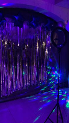 a stage set up for a party with purple lights and streamers on the wall