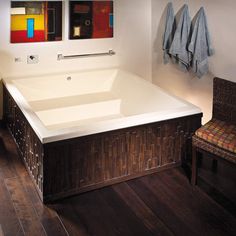 a large white bath tub sitting next to a wooden chair and two mirrors on the wall